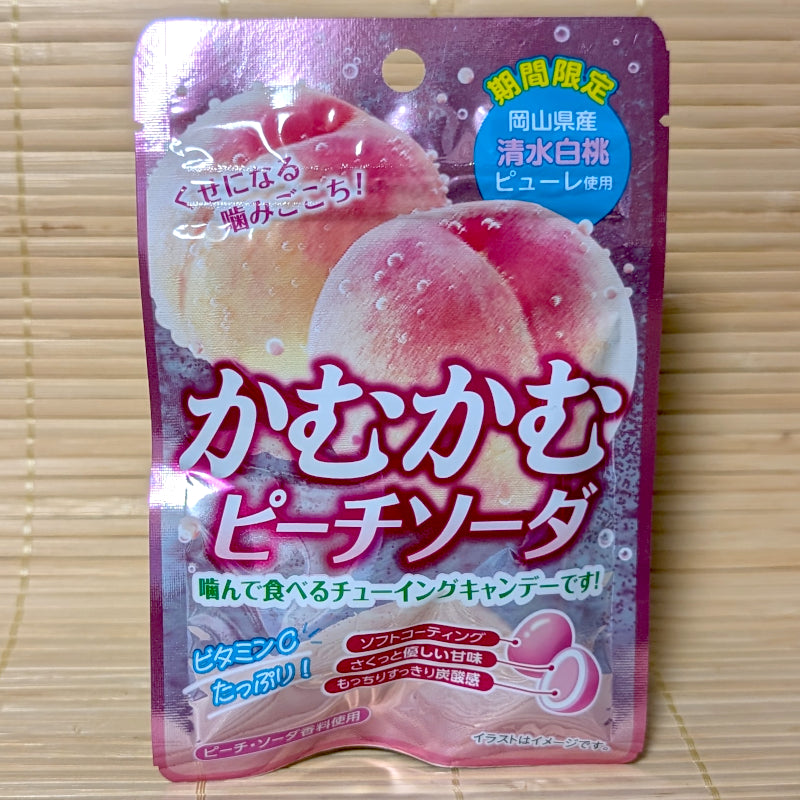 A metallic purple and pink resealable pouch of limited edition Kamu Kamu Peach Soda chewable candy featuring juicy white peaches on a tatami background.