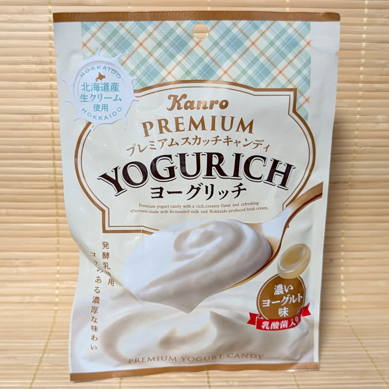 A cream-colored bag of Kanro Premium Yogurich candy featuring a spoonful of thick yogurt and an illustration of Hokkaido. Displayed on a tatami background.