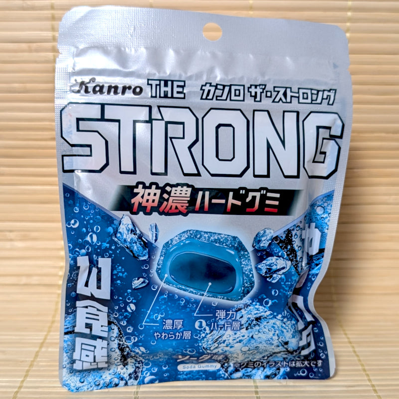 A silver and blue resealable pouch of Kanro THE STRONG gummies featuring a cross-section of the double-layer gem-shaped soda gummy.