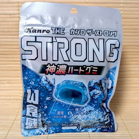 A silver and blue resealable pouch of Kanro THE STRONG gummies featuring a cross-section of the double-layer gem-shaped soda gummy.