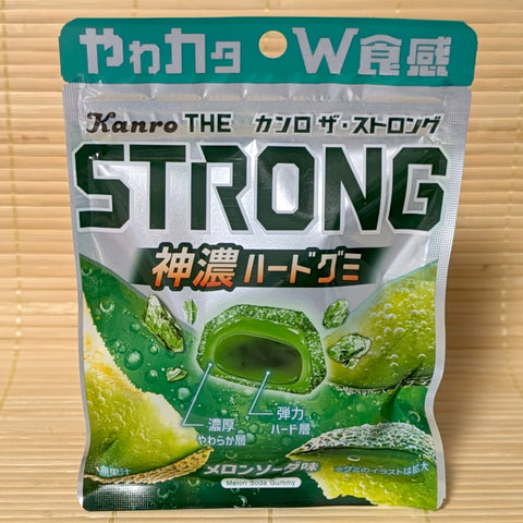 A pouch of THE Strong Melon Soda Gummy showing cross-section graphic of the dual-layer soft and hard texture, resting on a bamboo mat.