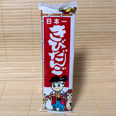 Japanese Kibi Dango dagasi snack package with cartoon Momotoro character. Displayed on a bamboo mat background.