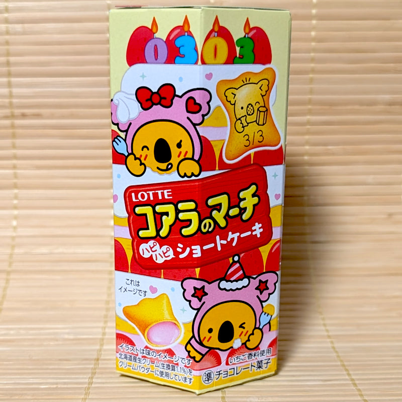 A yellow hexagonal box of Koala no March featuring a large strawberry cake and koalas wearing pink party hats.