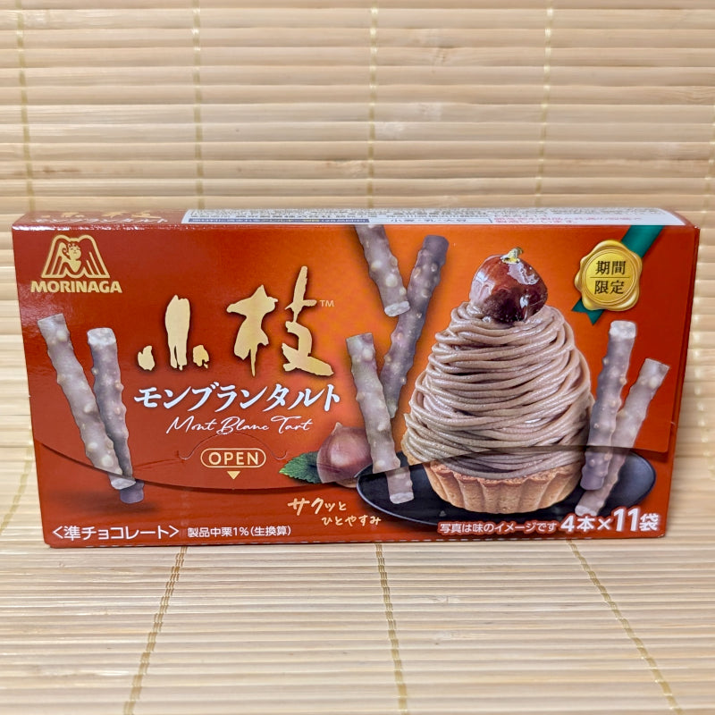 A warm reddish-orange box of Morinaga Koeda Chestnut Mont Blanc Tart chocolates displaying a Mont Blanc dessert graphic on a bamboo mat background.