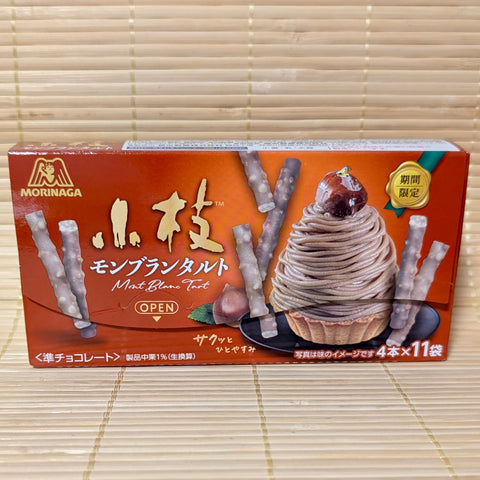 A warm reddish-orange box of Morinaga Koeda Chestnut Mont Blanc Tart chocolates displaying a Mont Blanc dessert graphic on a bamboo mat background.
