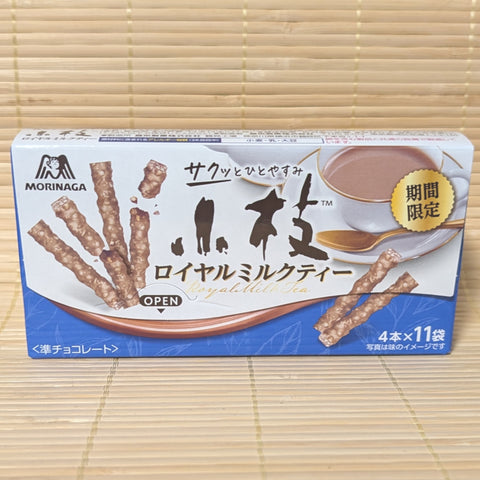 A blue and white box of Morinaga Koeda Royal Milk Tea chocolate featuring graphics of the chocolate branches next to a cup of milk tea.