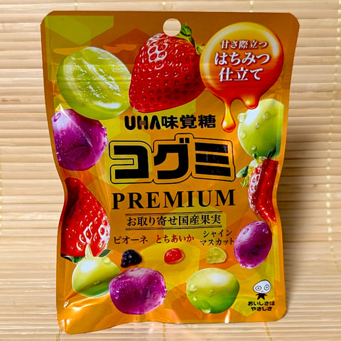 A golden yellow 75g pouch of Kogumi PREMIUM Japanese Honey Fruit Mix showing strawberries, grapes, and mini fruit gummies on a bamboo background.   