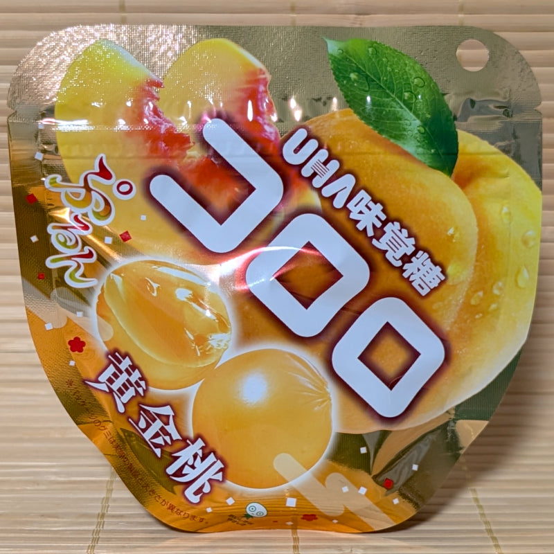 A pack of UHA brand Kororo Golden peach gummies displayed on a wooden surface
