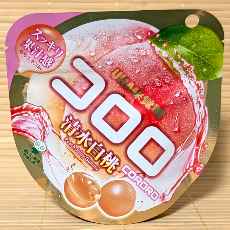 A pink and gold pouch of Kororo Shimizu White Peach Juicy Gummy featuring ripe white peach graphics on a bamboo background.