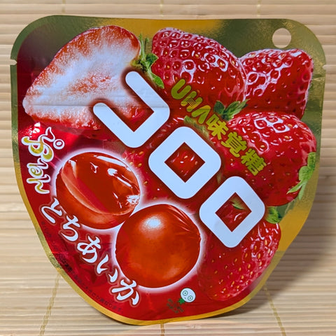 A pack of UHA Kororo Tochiaika strawberry gummy candy. Displayed on a wooden surface