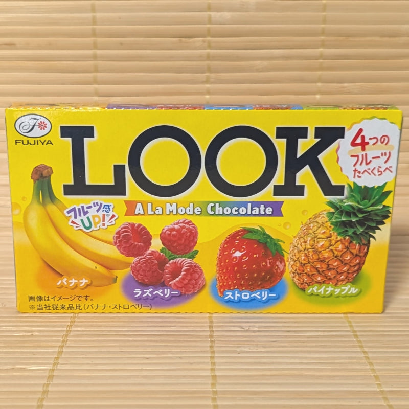 A 46g box of Fujiya LOOK A La Mode chocolate featuring four fruit varieties: Banana, Raspberry, Strawberry, and Pineapple, resting on a bamboo mat.