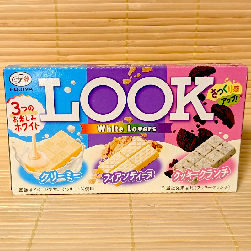 A 43g box of Fujiya LOOK White Lovers chocolate featuring three varieties: Creamy White, Crispy Feuillantine, and Cookie Crunch, resting on a bamboo mat.