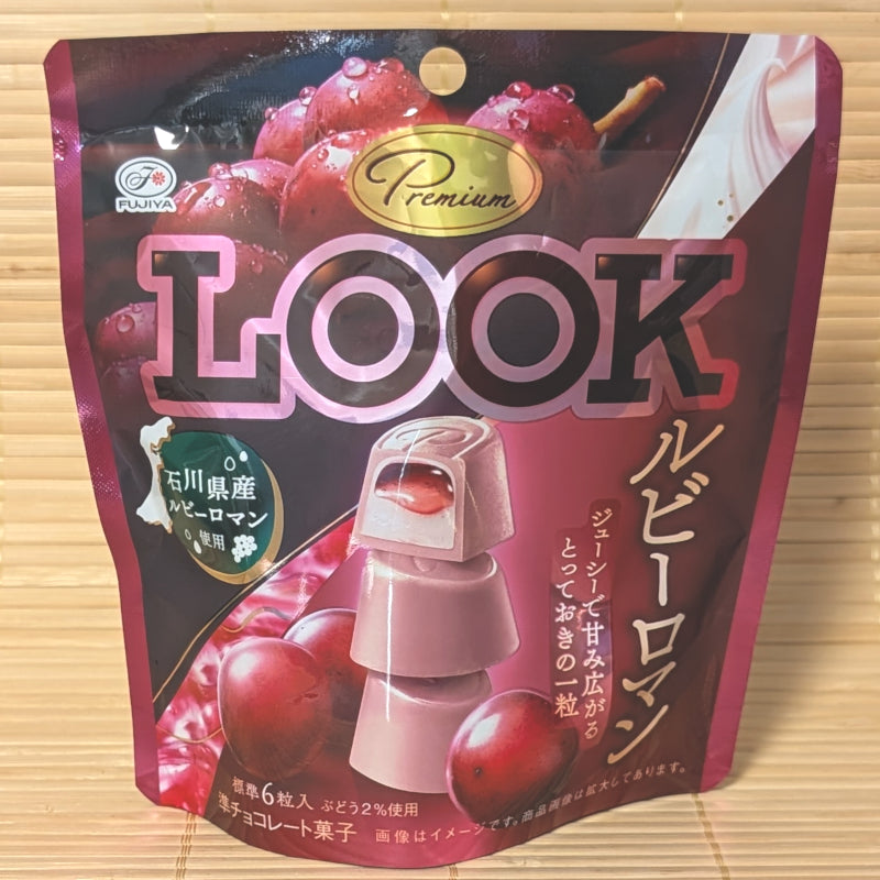 A deep pink 40.8g pouch of Fujiya LOOK Premium Ruby Roman Grape chocolates with liquid fruit filling graphics on a bamboo mat.