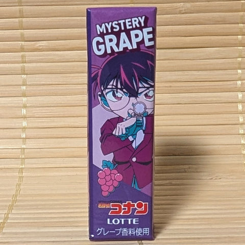 A deep purple pack of Lotte Mystery Grape gum on a tatami background featuring a Detective Conan character checking their watch.