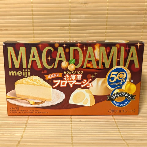 A dark red 50th anniversary box of Meiji Macadamia Chocolate Hokkaido Fromage featuring cheesecake graphics on a bamboo background.   