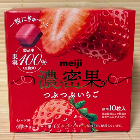 A bold red box of Meiji Strawberry Fruit chocolate showing a two-tone chocolate piece and fresh strawberry graphics.