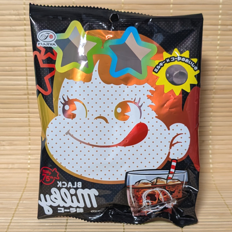 A bold red and black 64g bag of Fujiya Black Milky Cola candy featuring Peko-chan wearing star-shaped sunglasses and a glass of cola on a bamboo mat background.