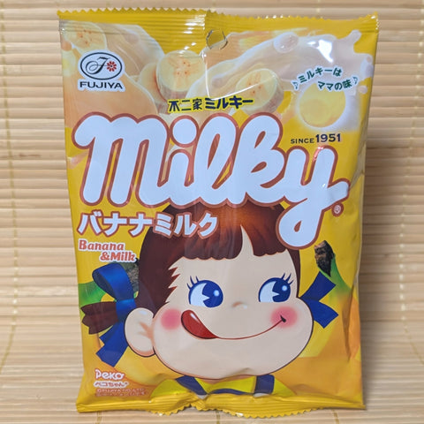 A yellow Fujiya Milky bag on a tatami background featuring Peko-chan and splashing banana milk graphics.