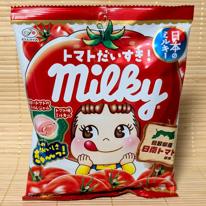 A vibrant red bag of Fujiya Milky Tomato candy featuring Peko-chan wearing a tomato hat and a diagram of the jam center.