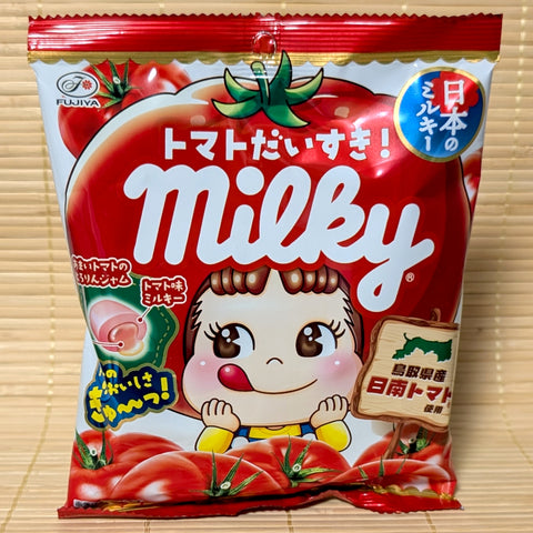 A vibrant red bag of Fujiya Milky Tomato candy featuring Peko-chan wearing a tomato hat and a diagram of the jam center.