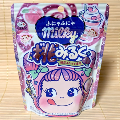 A cute pink 36g pouch of Fujiya Funya-Funya Milky Peach Milk soft candy featuring Peko-chan illustrations on a bamboo mat background.