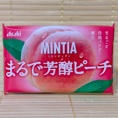 A vibrant pink pocket-sized case of Asahi Mintia Mellow White Peach featuring a large peach illustration. Displayed on a tatami background.