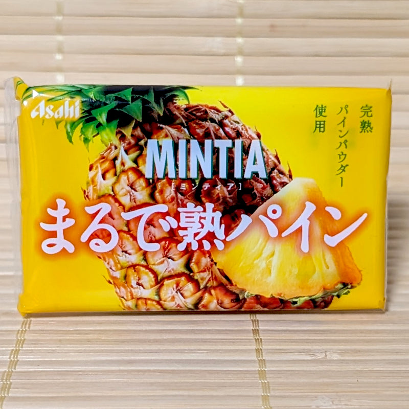 A bright yellow pocket-sized case of Asahi Mintia Ripe Pineapple featuring a large pineapple illustration. Displayed on a tatami background.