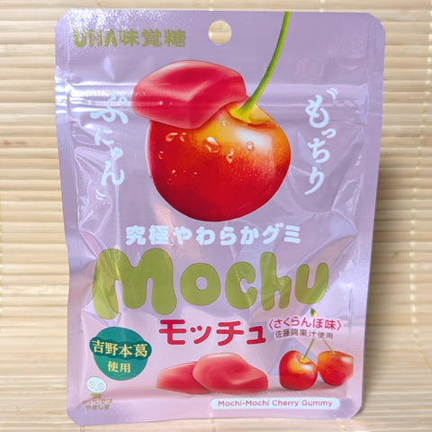 A light purple pouch of UHA Mochu gummy on a tatami background featuring a large Sato Nishiki cherry and soft, red gummy pieces.