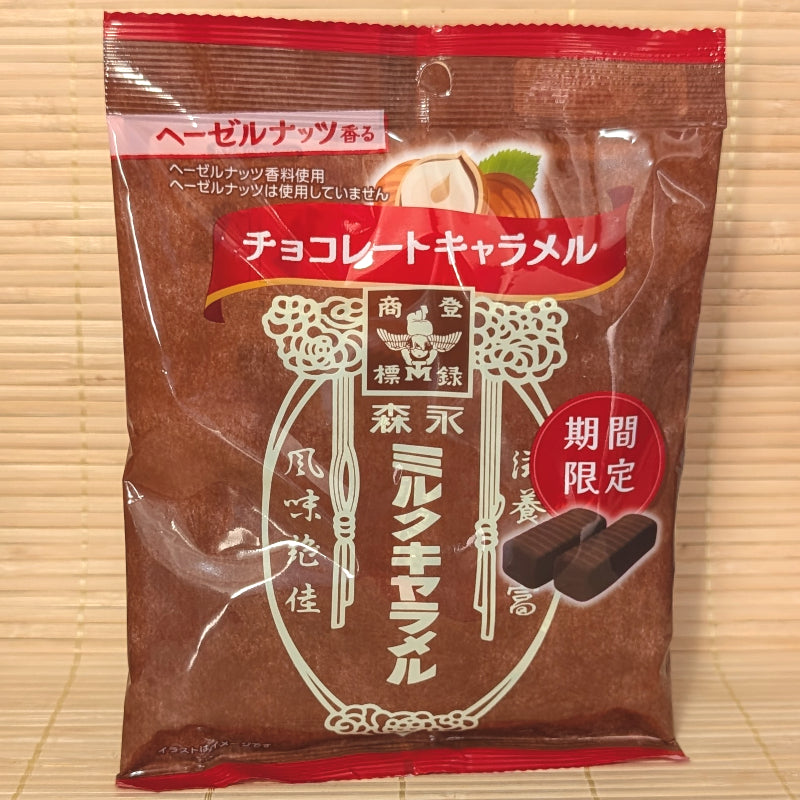 A brown 69g bag of Morinaga Chocolate Caramel showing hazelnuts, classic Morinaga retro branding, and dark chocolate caramel pieces on a bamboo mat background.