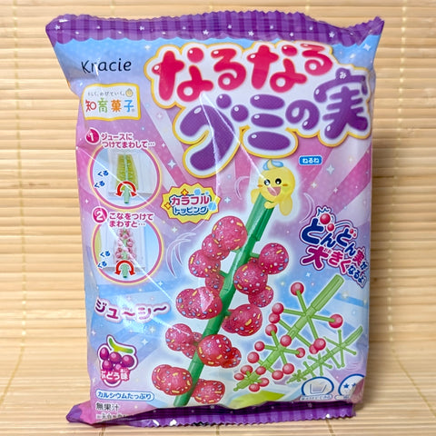 A colorful 15g pack of Kracie Naru Naru Gumi no Mi DIY Grape Candy Kit displaying a gummy vine and powder trays on a bamboo mat.