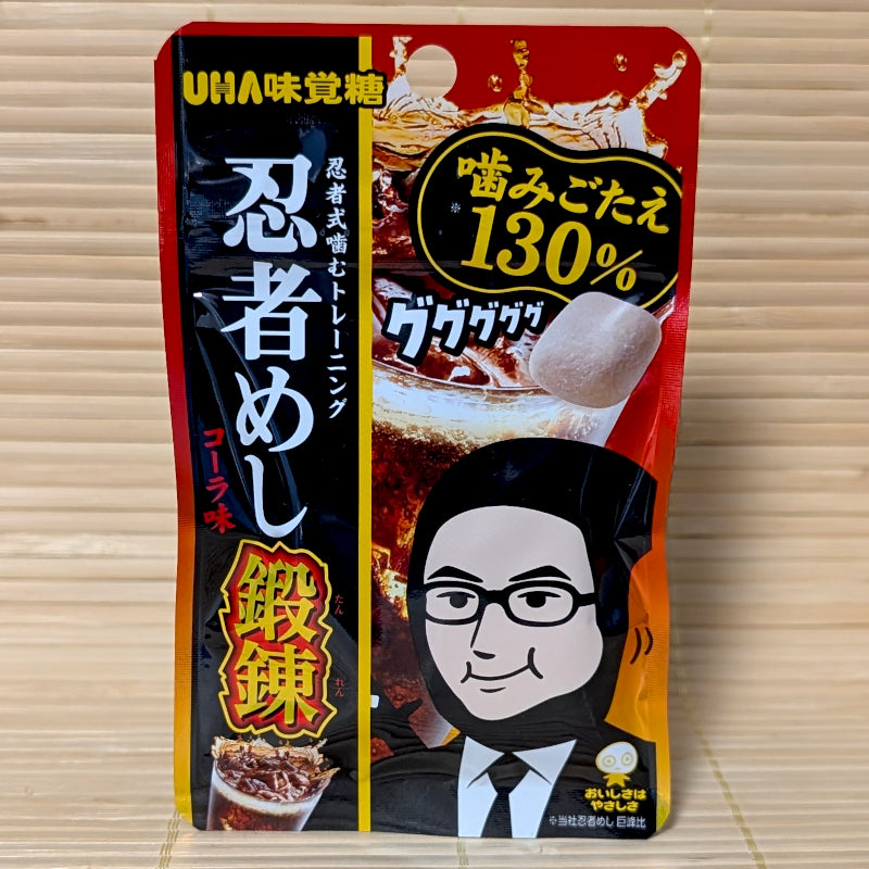 A slim red and black pouch of Ninja Meshi Extra Tough Cola gummies on a tatami background, featuring a ninja character and 130% toughness callout.