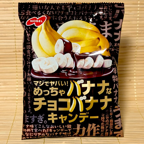 A black bag of Nobel Choco Banana Candy showing sliced bananas with rich chocolate sauce graphics on a bamboo background.   