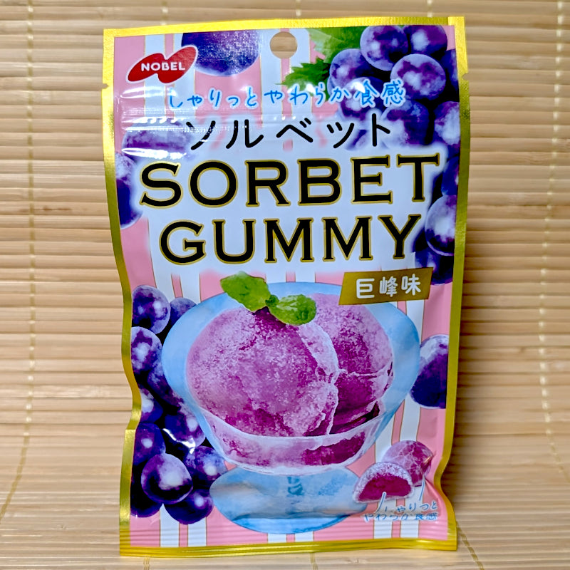 A pink and gold resealable pouch of Nobel Sorbet Gummy Kyoho Grape flavor showing a glass bowl of purple sorbet on a tatami background.