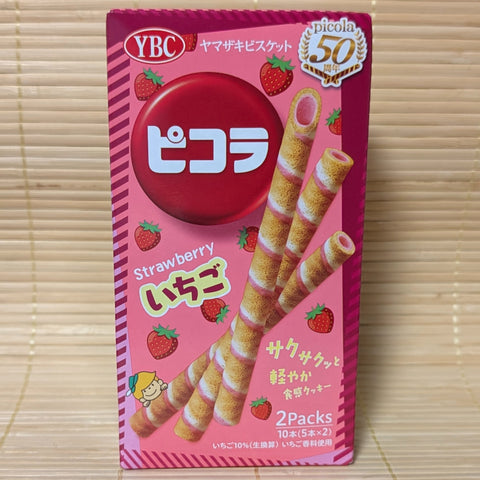 A red and pink package of YBC Strawberry Picola cookie and chocolate sticks, displayed on a wooden surface.
