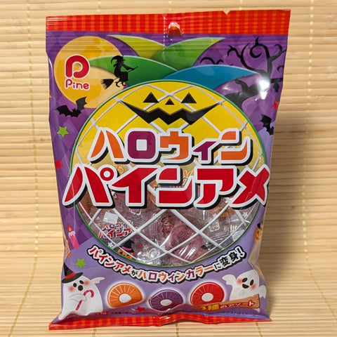 A purple 98g bag of Pine Halloween Pine-Ame candy showing orange, purple, and red pineapple-shaped candy rings on a bamboo mat.