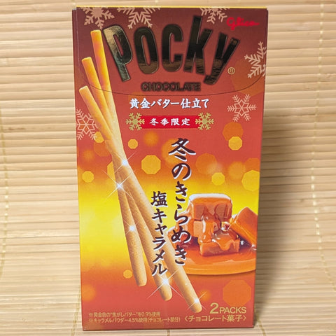 A warm orange and gold box of Glico Pocky Winter Butter Salted Caramel with caramel graphics on a bamboo background.