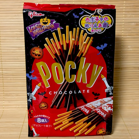 A festive black and red Halloween bag of Glico Chocolate Pocky showing jack-o'-lanterns, bats, and mini foil packs on a bamboo background.