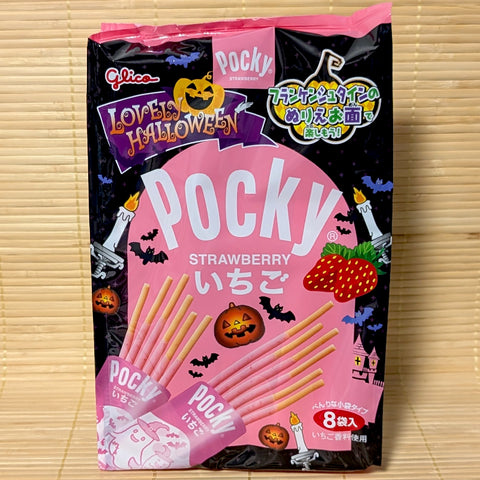 A festive pink and black Halloween bag of Glico Strawberry Pocky showing jack-o'-lanterns, ghosts, and mini foil packs on a bamboo background.