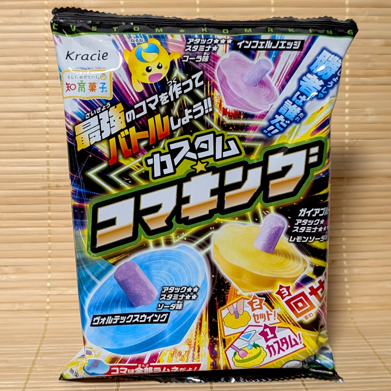 An action packed 20g package of Kracie Custom Koma King DIY candy kit showing colorful illustrations of blue, yellow, and purple edible spinning tops.