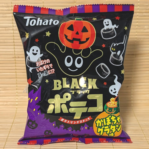A black and purple 50g bag of Poteko Black Halloween Kabocha Gratin potato rings featuring ghosts and jack-o'-lanterns on a bamboo mat.