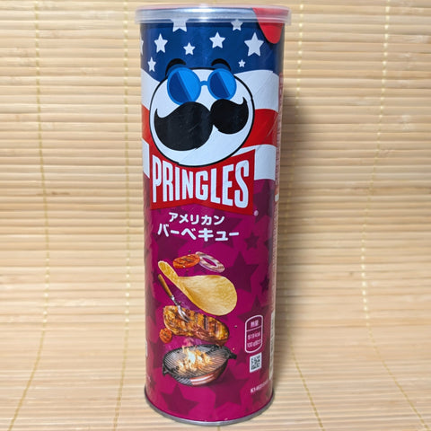 A tall purple and blue Pringles can with an American flag theme and an illustration of grilled meat and BBQ chips. Displayed on a tatami surface.