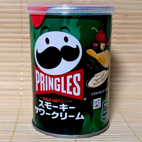 A dark green Pringles short can featuring a mild hot smoky sour cream flavor with illustrations of chili peppers and sour cream.