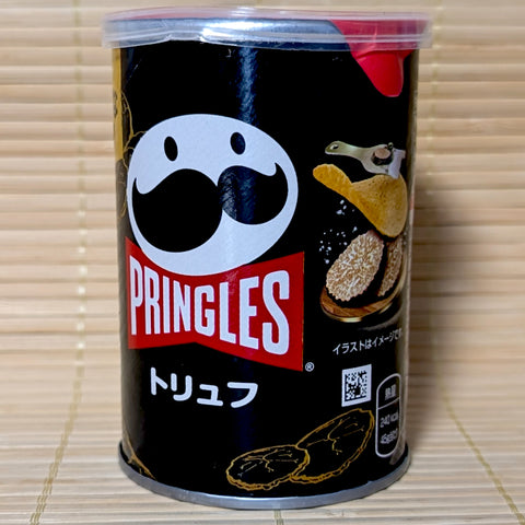 A black 45g stout can of Japanese Pringles Premium Black Truffle chips on a bamboo mat background.