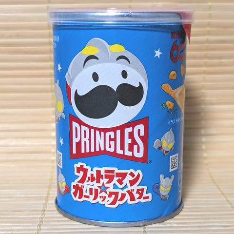 A short blue 45g canister of Japanese Pringles Garlic Butter potato chips featuring a superhero styled mascot and Ultraman characters on a tatami background.