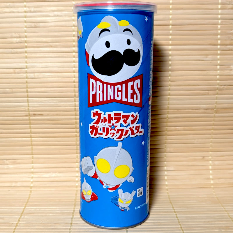 A tall blue 95g can of Japanese Pringles Garlic Butter potato chips featuring a superhero-styled mascot and Ultraman characters on a tatami background.