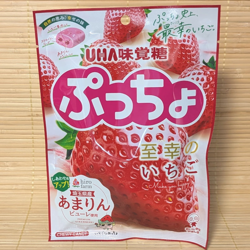 A white and red 67g bag of UHA Mikakuto Puccho showing fresh Amarin strawberries and candy graphics on a bamboo mat.