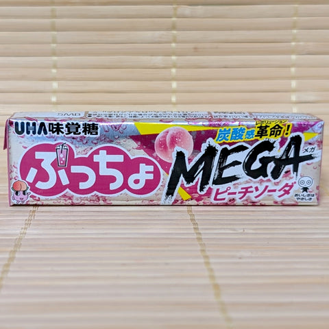 A metallic silver and pink stick of Puccho MEGA Peach Soda featuring a "carbonation revolution" callout and a whole peach illustration.