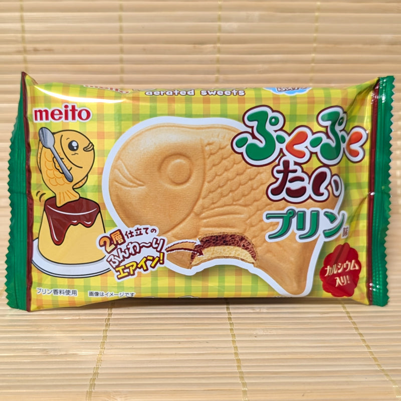 A yellow and green package of Meito Puku Puku Tai showing a fish-shaped wafer and a Japanese pudding graphic, on a tatami background.