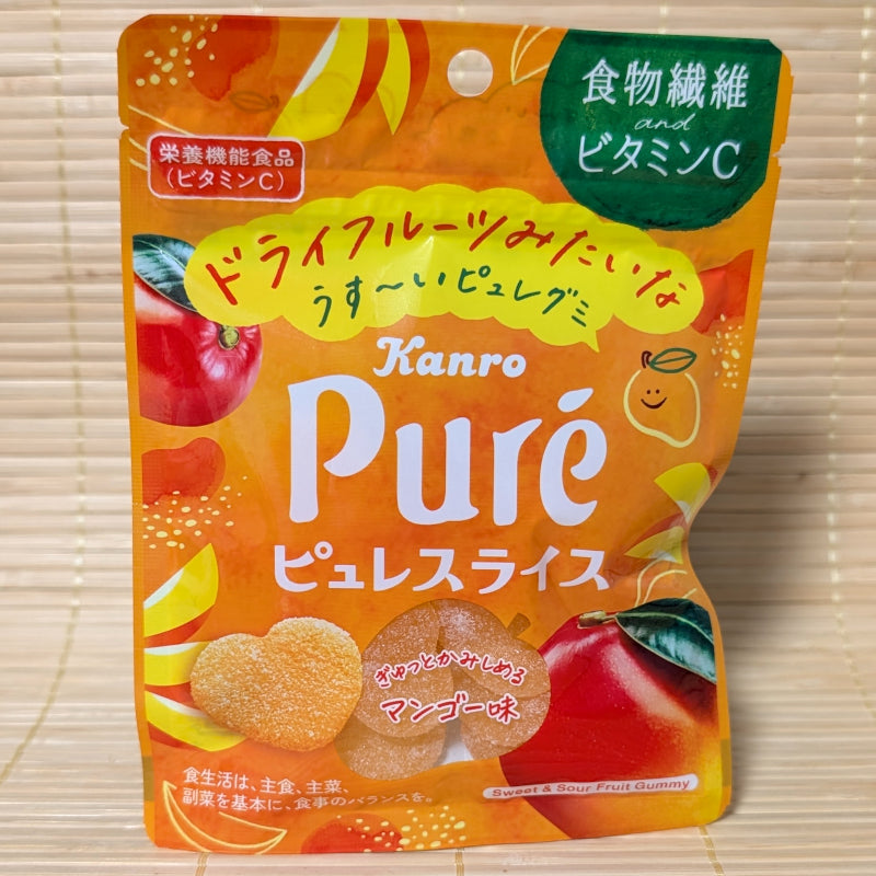 A bright orange and green resealable pouch of Kanro Puré Gummy Mango Slice, showing heart-shaped gummies and fresh mango graphics on a tatami background.
