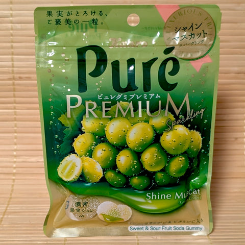 A light green pouch of Puré Gummy Premium Shine Muscat Sparkling Gummy featuring green grape graphics and a gold badge on a bamboo background.   